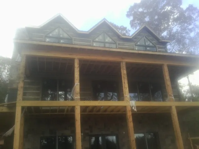 Dormers and porch framing on a large log home under construction — Roof Coating work by our crew in Foxhome