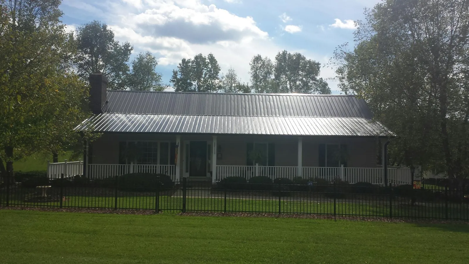 Gray metal roof on a brick ranch with a full width front porch — Gutter Guard Installation work by our crew in Foxhome