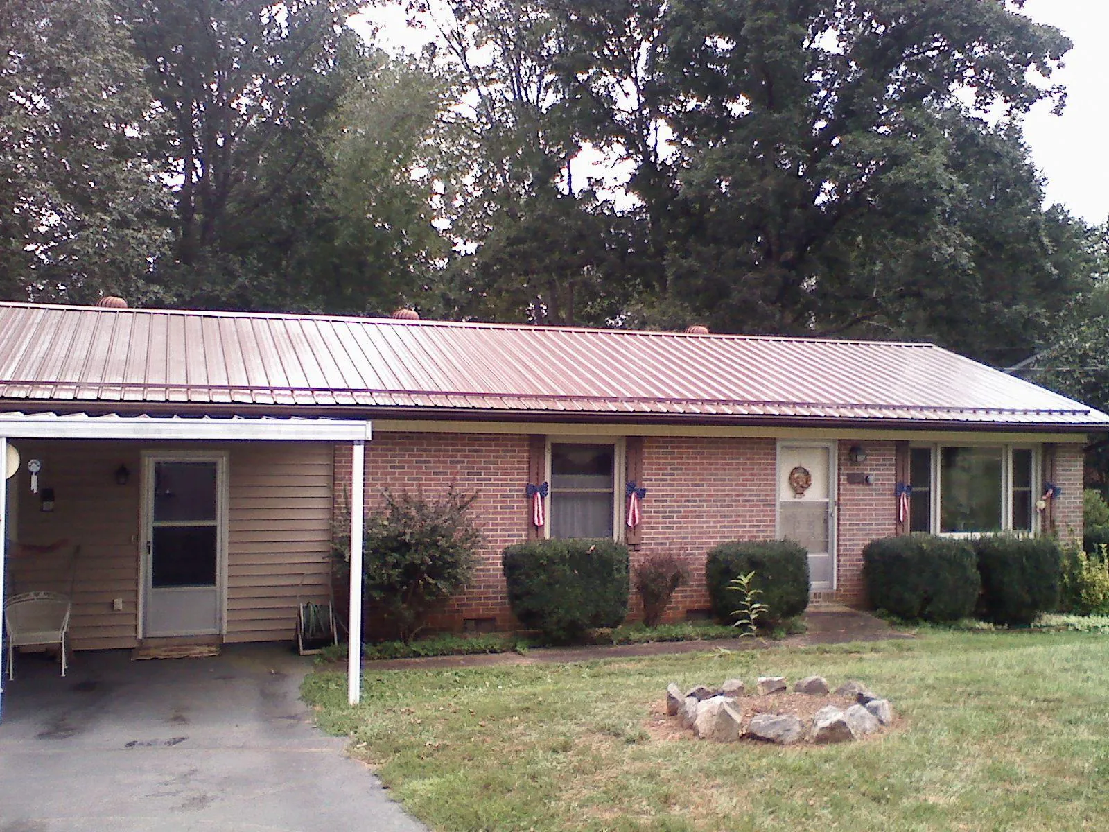 Bronze metal roof and carport on a brick ranch home — Roof Repair work by our crew in Foxhome