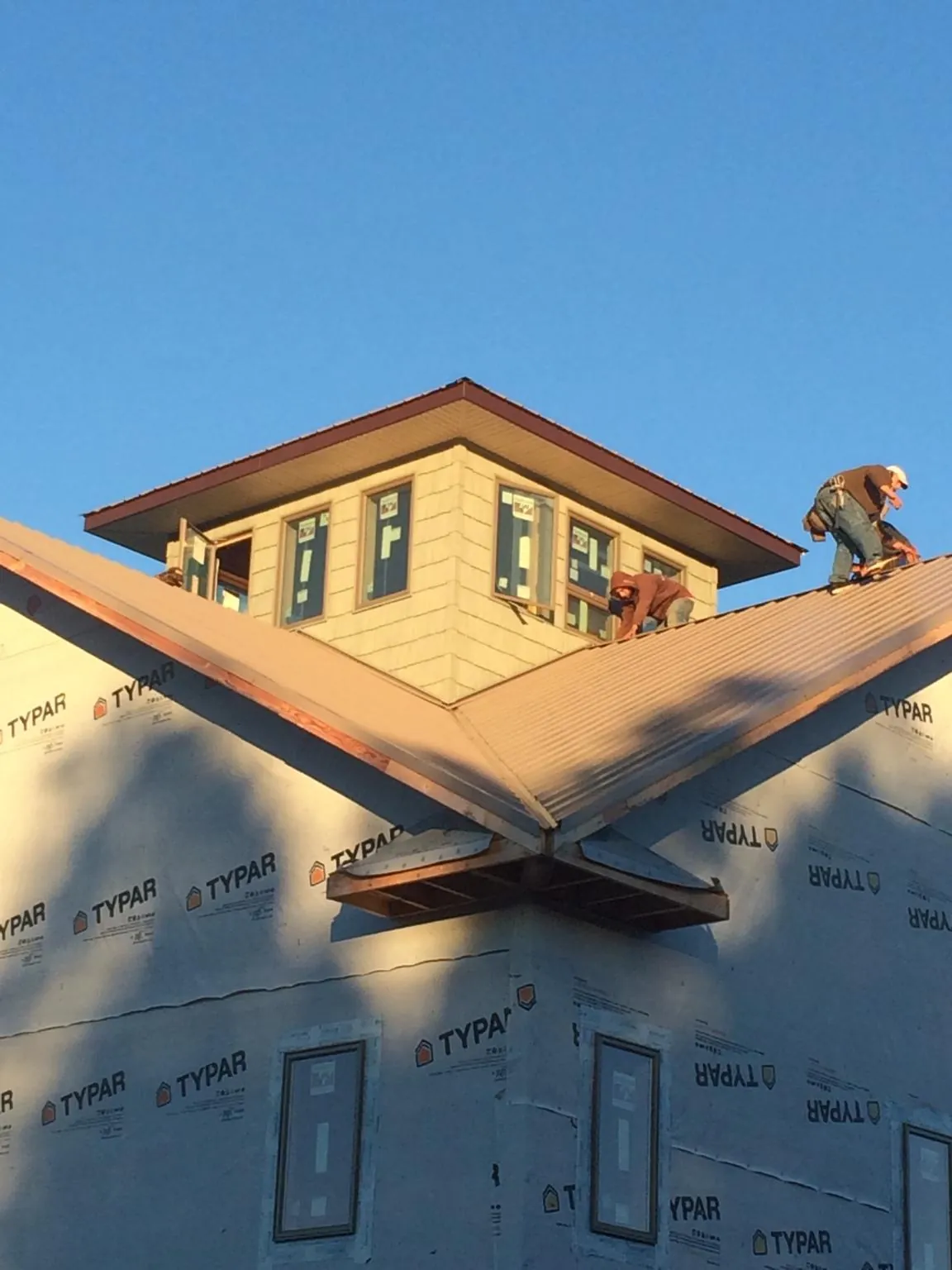Roofers working around a rooftop cupola on a new metal roof at sunset — Roof Waterproofing in Foxhome by Roofing Brothers